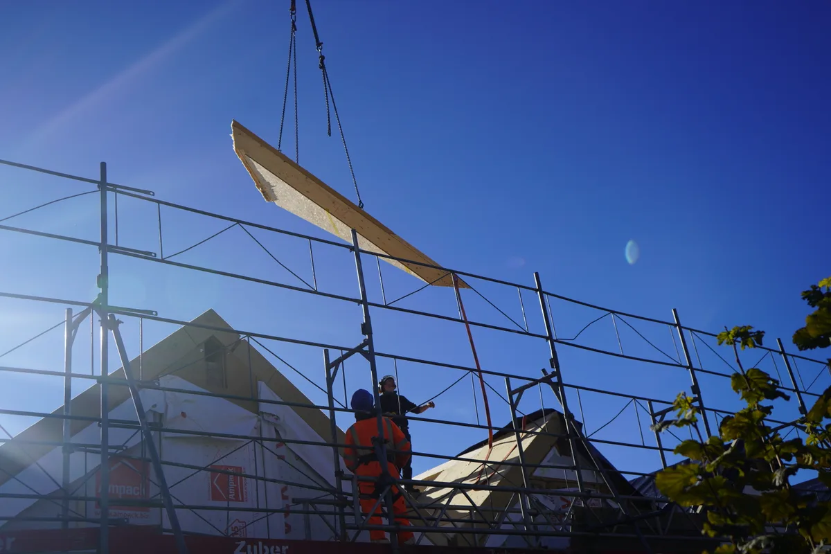 Zwei Bauarbeiter auf dem Dach des Bachtel Kulms nehmen Holzelemente in Empfang.
